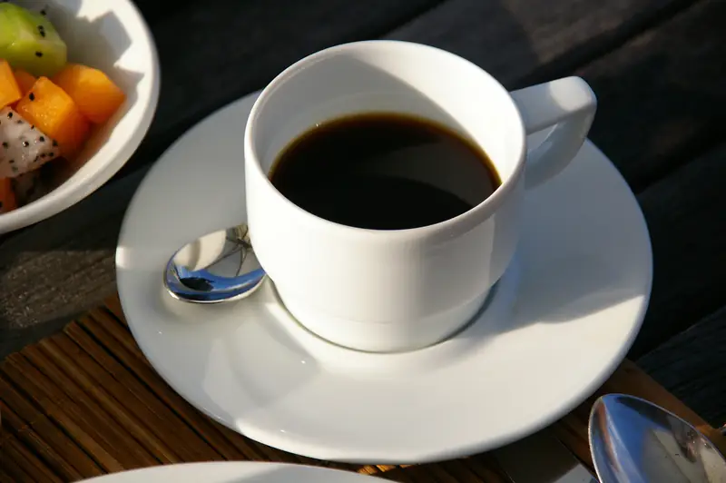 木のテーブルに置かれた白いカップのコーヒー